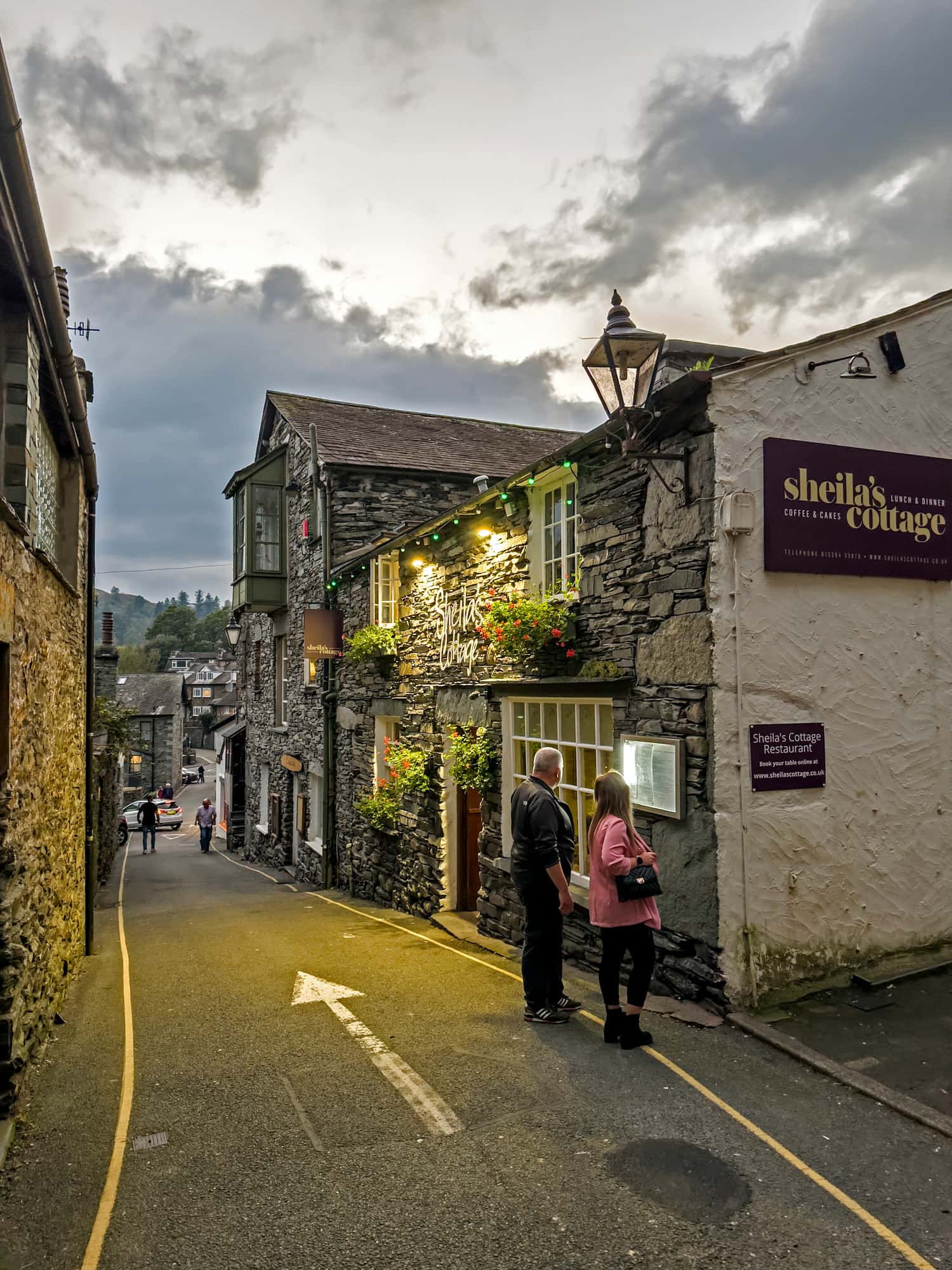 Foto van een sfeervol straatje in Ambleside, een populair dorp in het Lake District in Engeland. Met stenen huizen, gezellige restaurants en een authentieke dorpssfeer is dit een favoriete plek voor bezoekers tijdens een roadtrip.